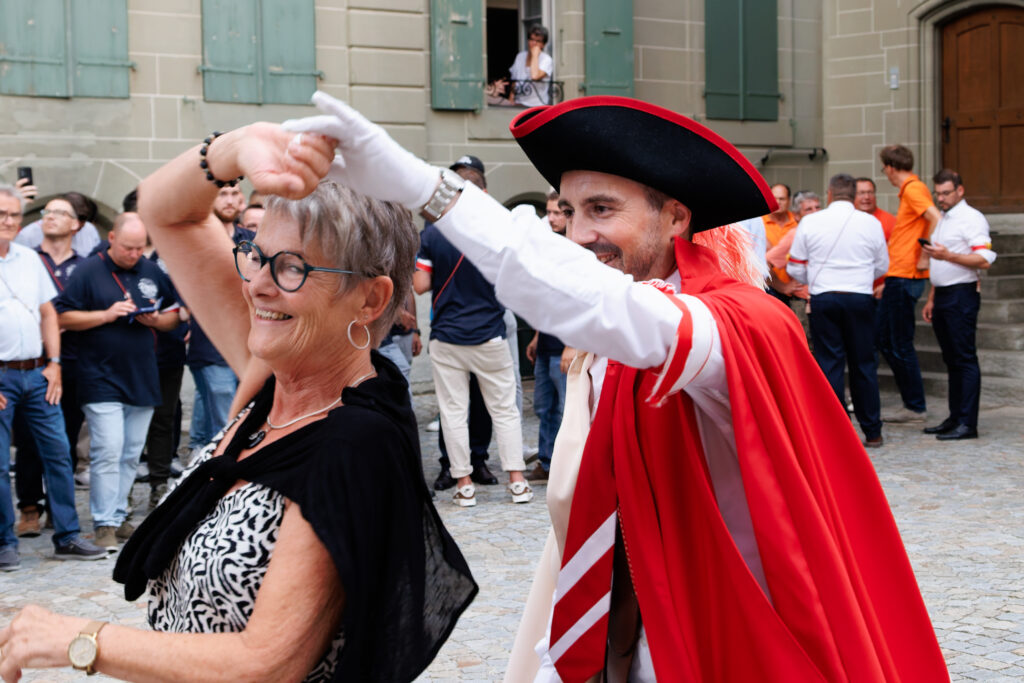 Homme en costume traditionnel rouge dansant avec une femme lors d'une fête