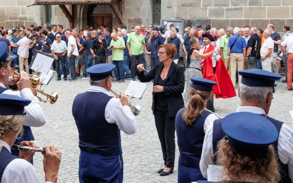 Cheffe d'orchestre dirigeant une fanfare en plein air