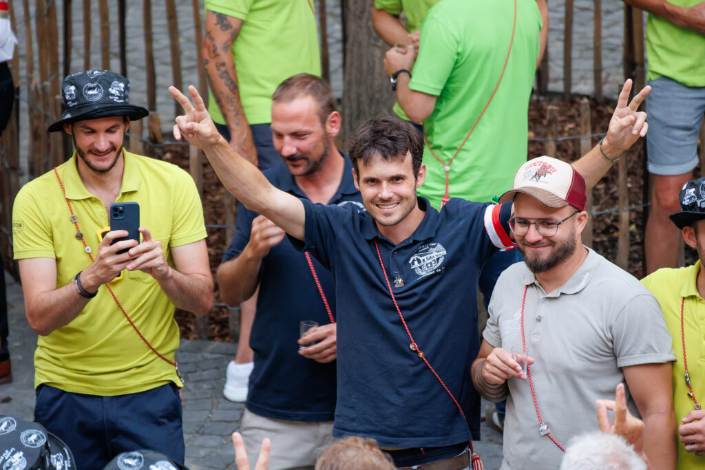 Homme souriant les bras levés entouré d'amis festifs