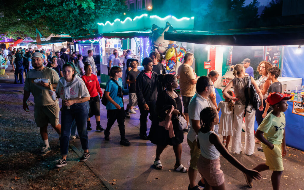 Foule animée lors d'une fête foraine nocturne illuminée