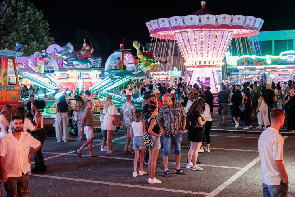 Foule animée dans une fête foraine illuminée la nuit