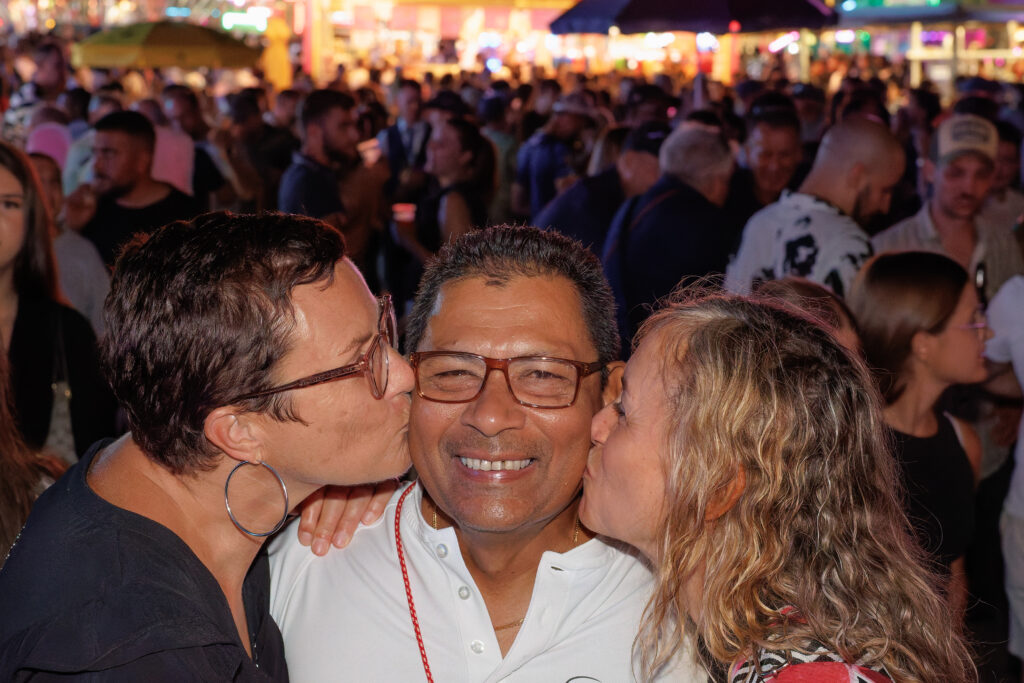 Deux femmes embrassant un homme souriant lors d'une fête