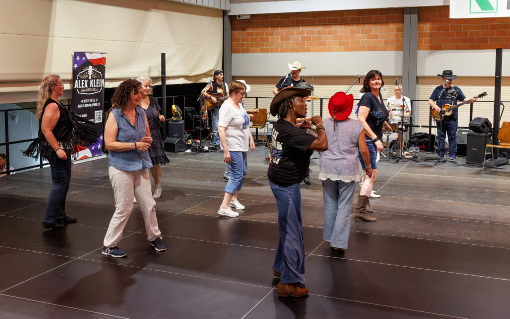 Groupe de personnes dansant le line dance country avec musiciens en fond