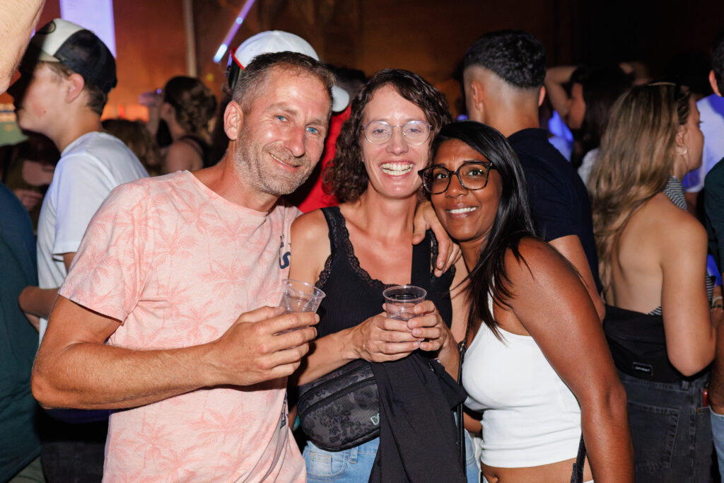 Trois amis souriants posent ensemble lors d'une soirée festive