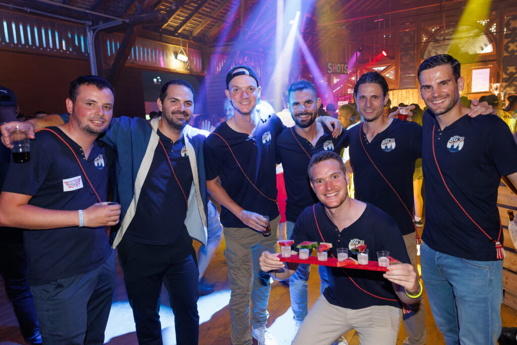 Groupe d'hommes en t-shirts BG's posant avec des shots en boîte de nuit