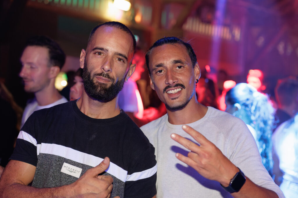 Deux hommes souriants posant ensemble en boîte de nuit