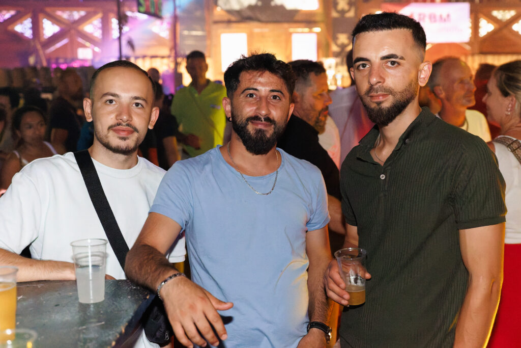 Trois hommes souriants posant ensemble lors d'une soirée festive