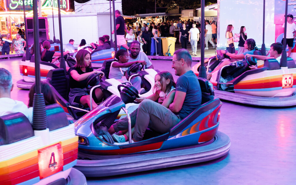 Famille souriante dans des autos tamponneuses lors d'une fête foraine