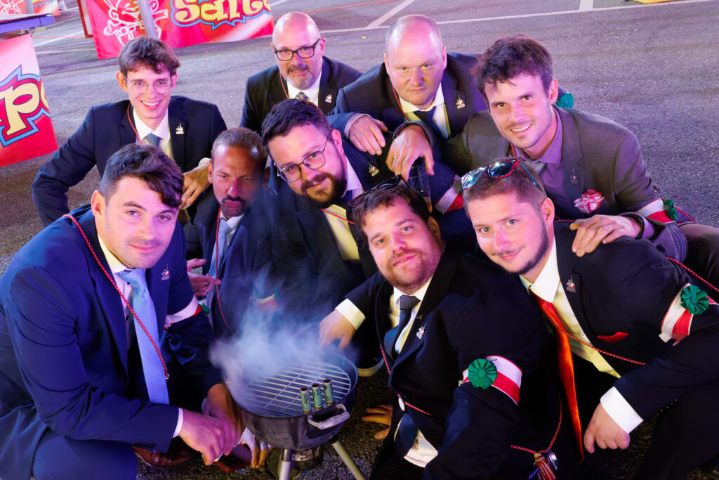 Groupe d'hommes en costume autour d'un barbecue lors d'une fête