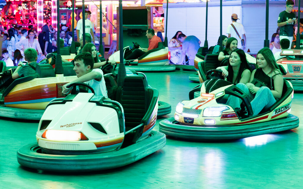Jeunes gens s'amusant sur des autos tamponneuses en fête foraine