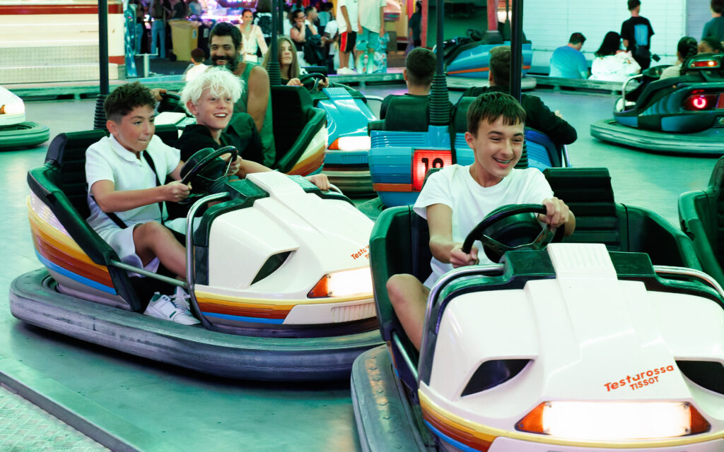 Adolescents souriants conduisant des autos tamponneuses dans une fête foraine