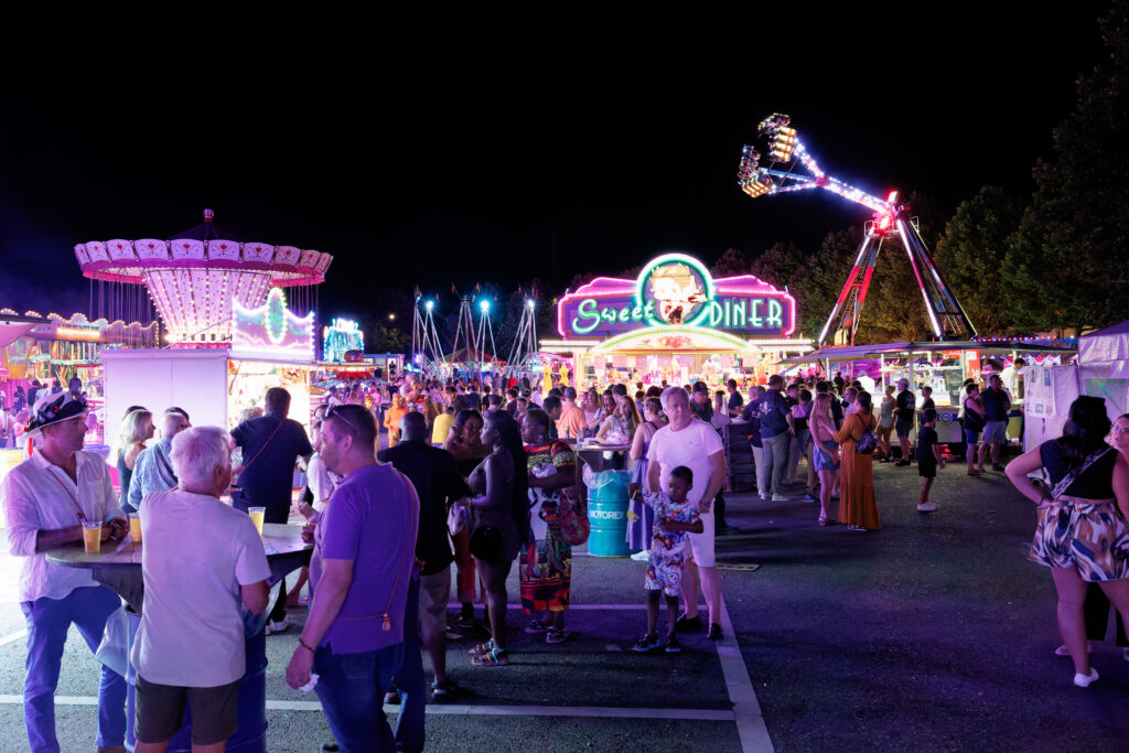 Foule animée dans une fête foraine illuminée la nuit